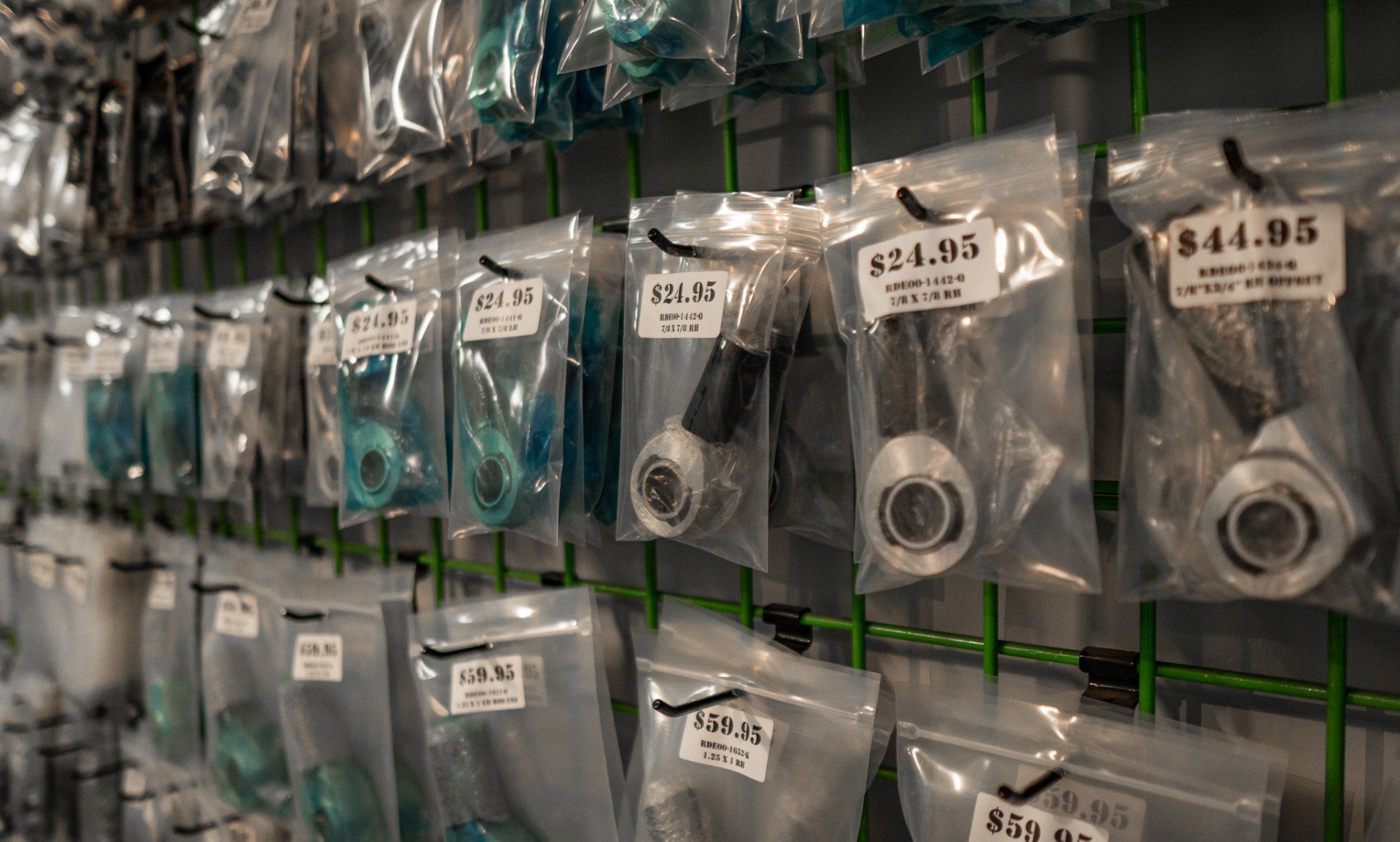 Various car parts, in plastic bags, hanging on a grid display. Prices are visible.
