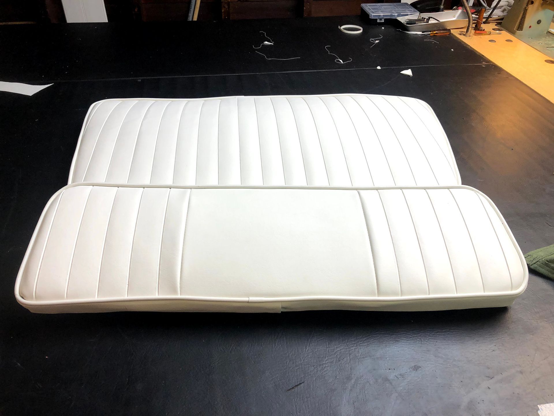 White vinyl boat seat with vertical stitching and light piping on a dark surface.