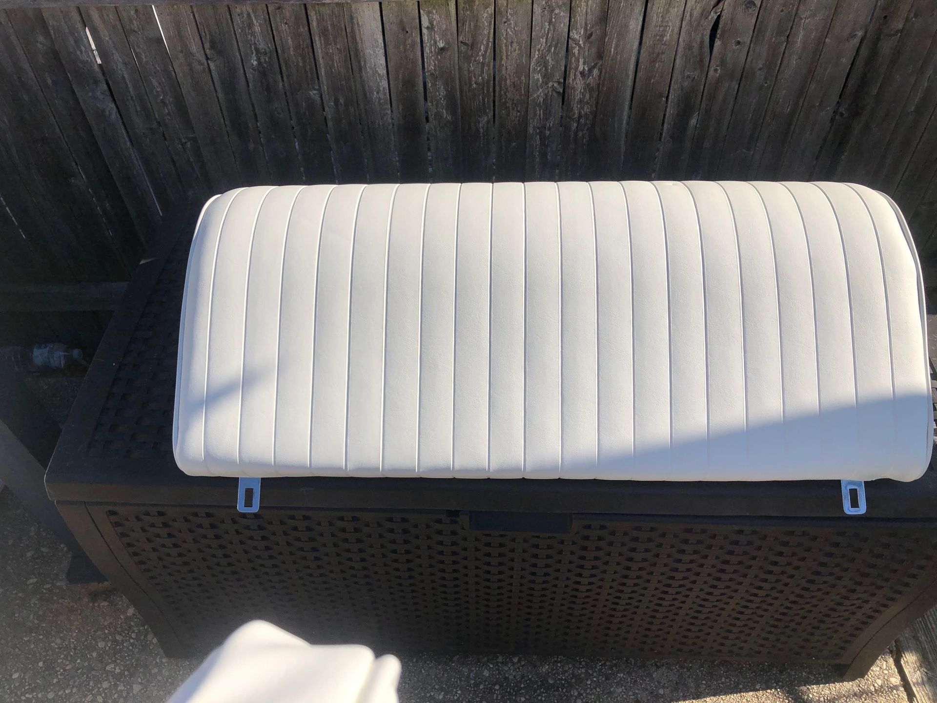 White, padded boat seat with vertical stitching, mounted on a dark brown storage box.