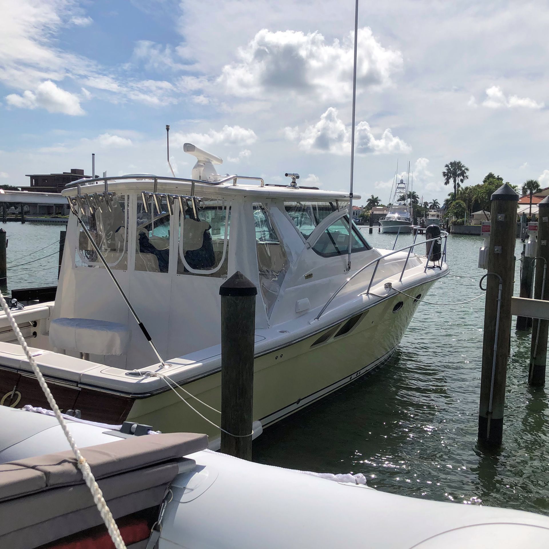 A white and light yellow boat docked at a pier on a sunny day.