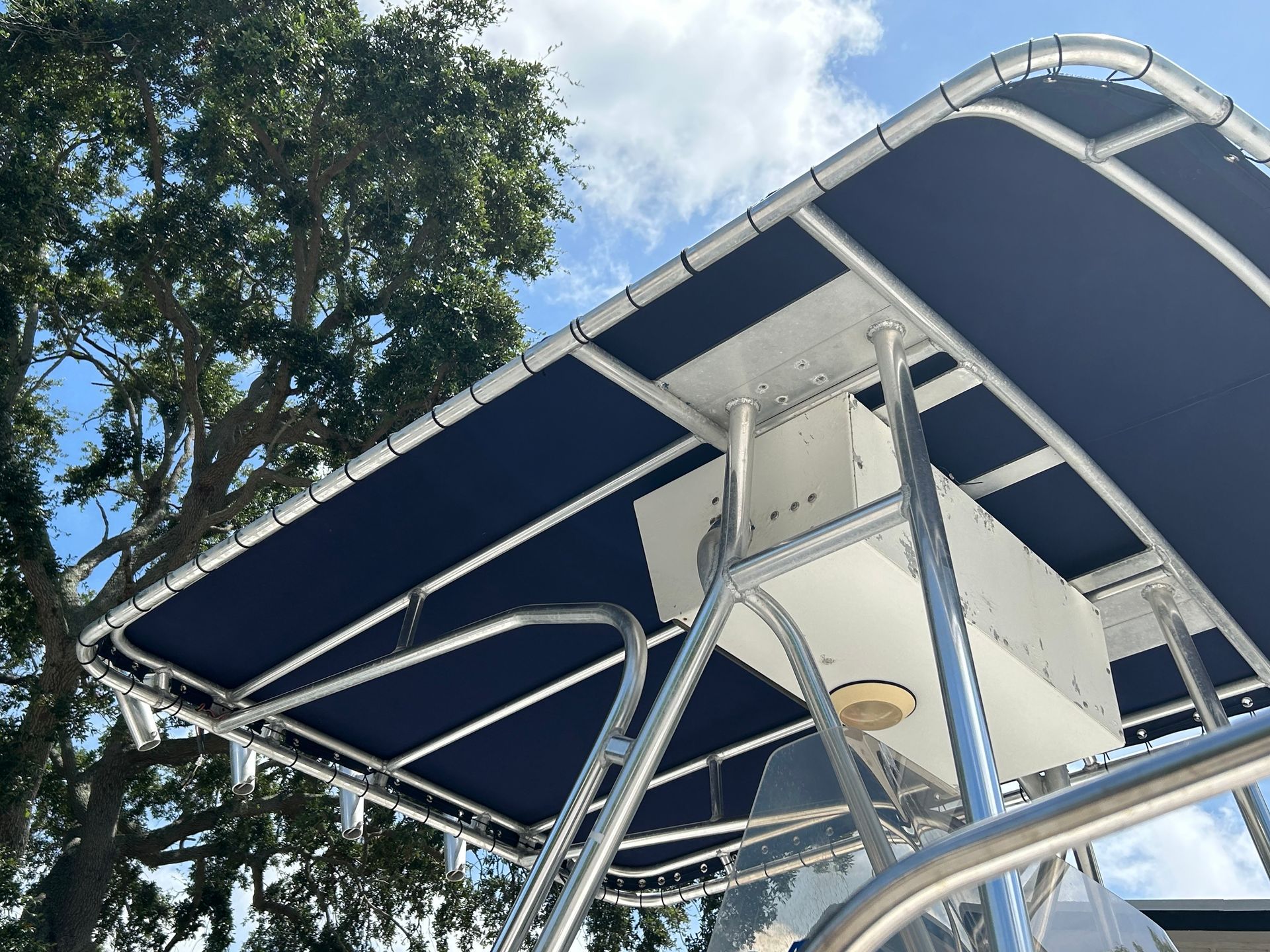 Blue boat canopy over a silver frame, with a white storage box.
