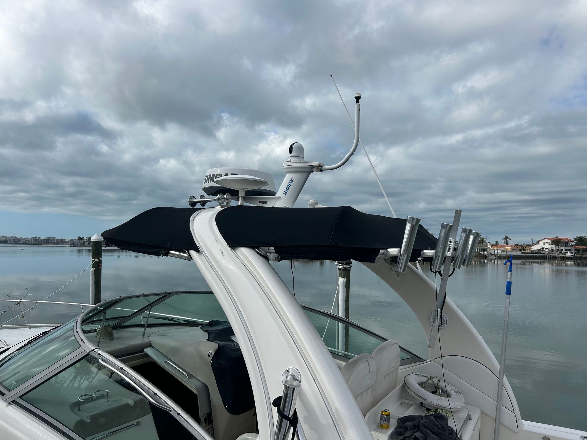 A boat's radar and antenna atop a black canopy, set on water with a cloudy sky.