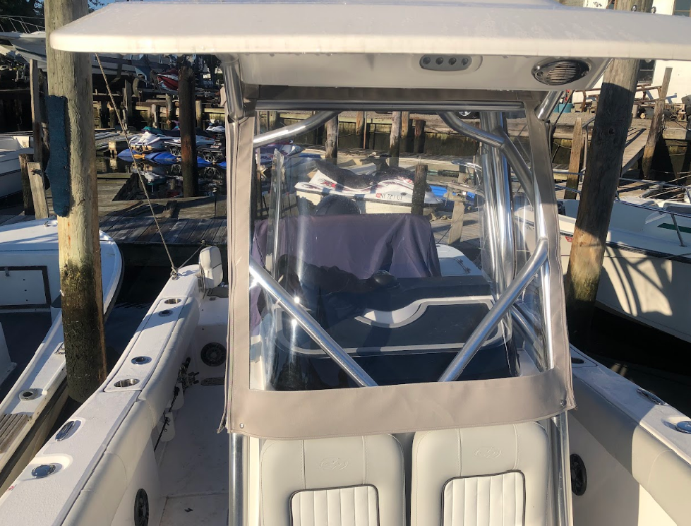 Boat cockpit with clear enclosure and overhead canopy, docked at a pier.