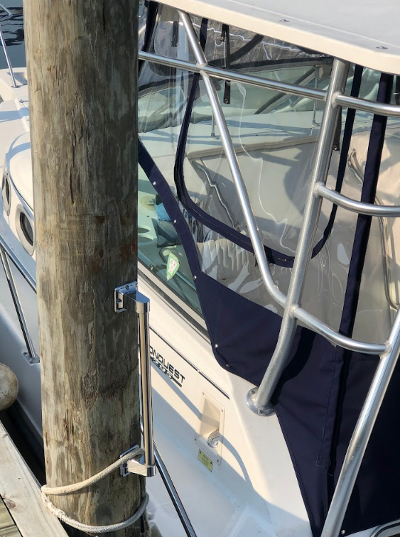 Boat docked at a pier, with a wooden post and clear vinyl window enclosure.