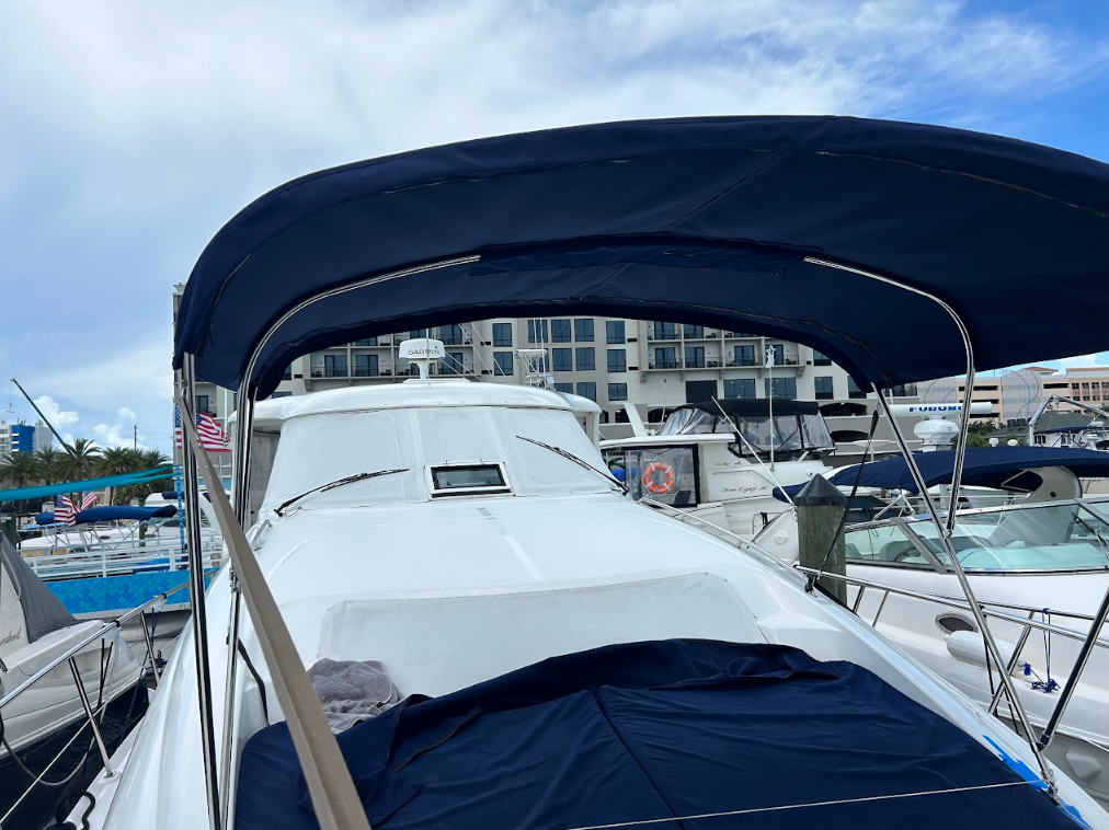 Boat with a blue canopy, docked at a marina.