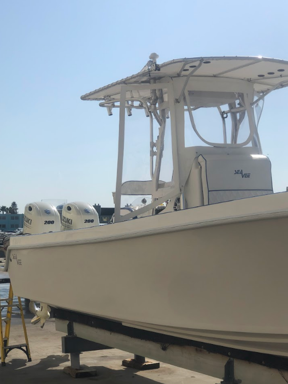 White boat on stands with twin outboard motors under a blue sky.