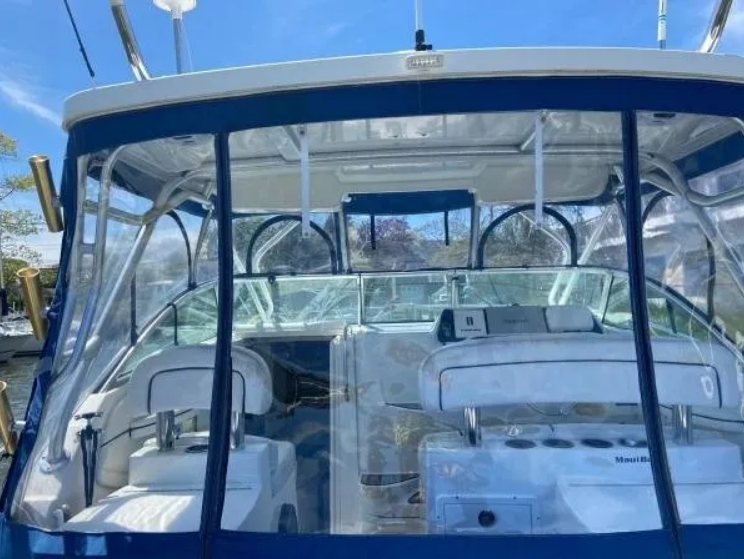 Boat interior with clear vinyl windows, blue trim, white seats, control panel.