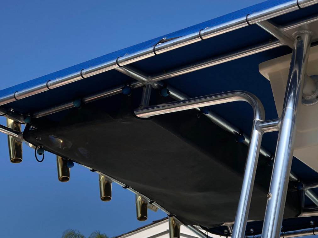 Interior view of a white boat's helm with windshield, rod holders, and a blue-sky background.