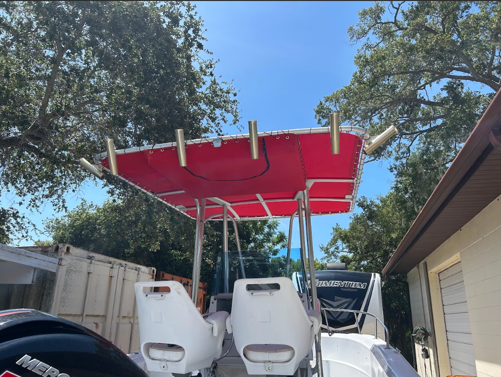 Boat with red canopy, fishing rod holders, and two white seats, outdoors in the sun.