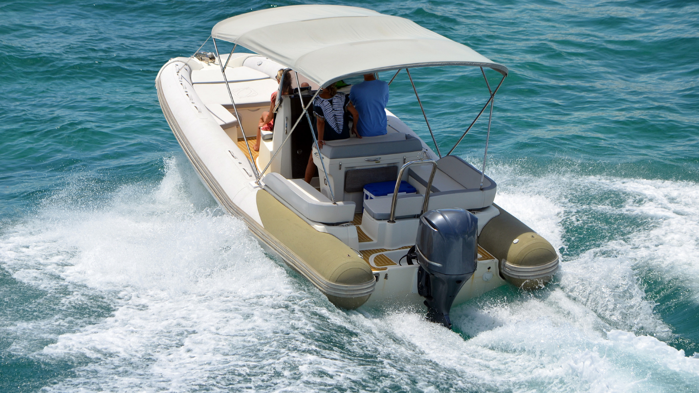 Motorboat speeding across the water, cream and tan colors, with two people aboard.