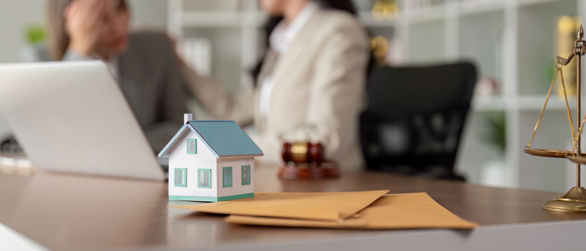 Model house and legal documents on desk during estate planning meeting.