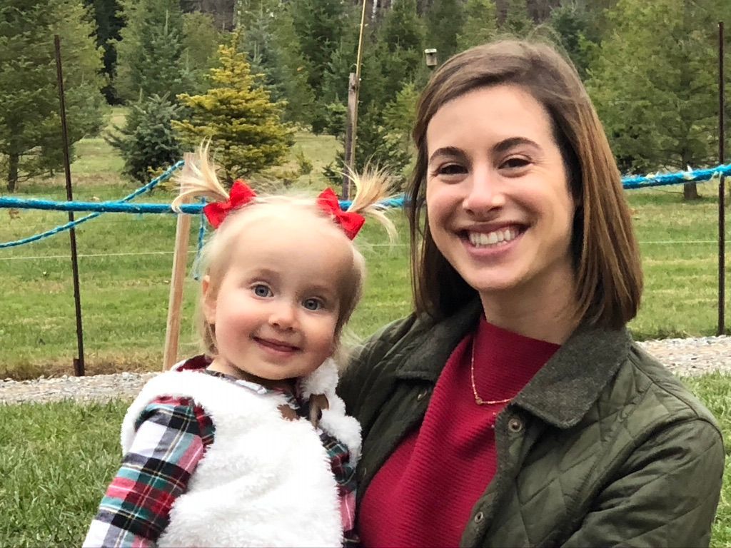A woman is holding a little girl in her arms and smiling.
