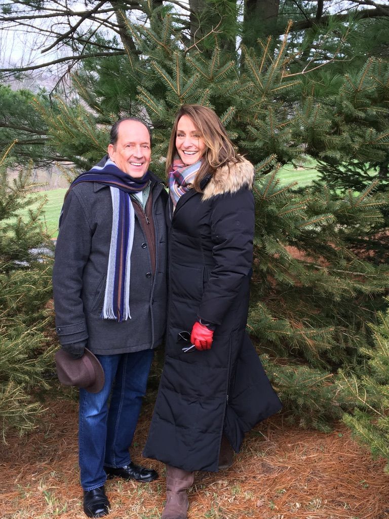 A man and a woman are posing for a picture in front of a christmas tree.