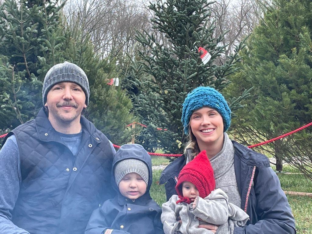 A family is posing for a picture in front of a christmas tree.
