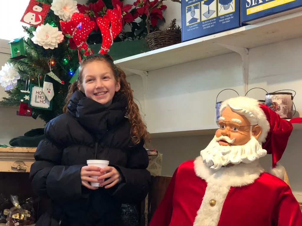 A young girl is standing next to a statue of santa claus.