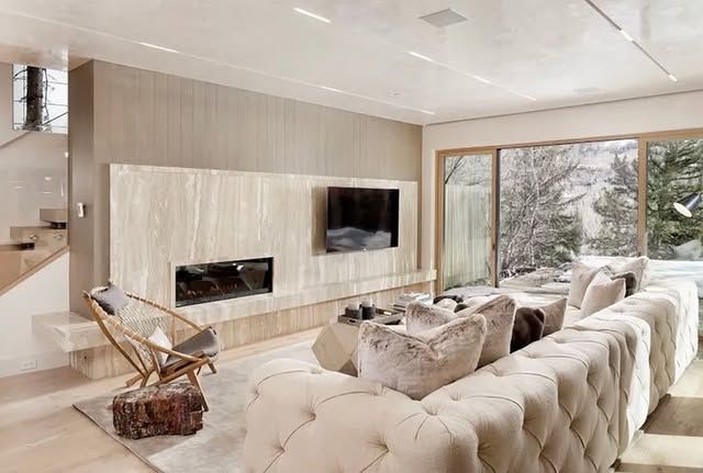 A living room with a large couch , fireplace and television.