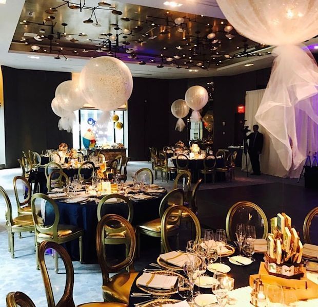 A large room with tables and chairs and balloons hanging from the ceiling