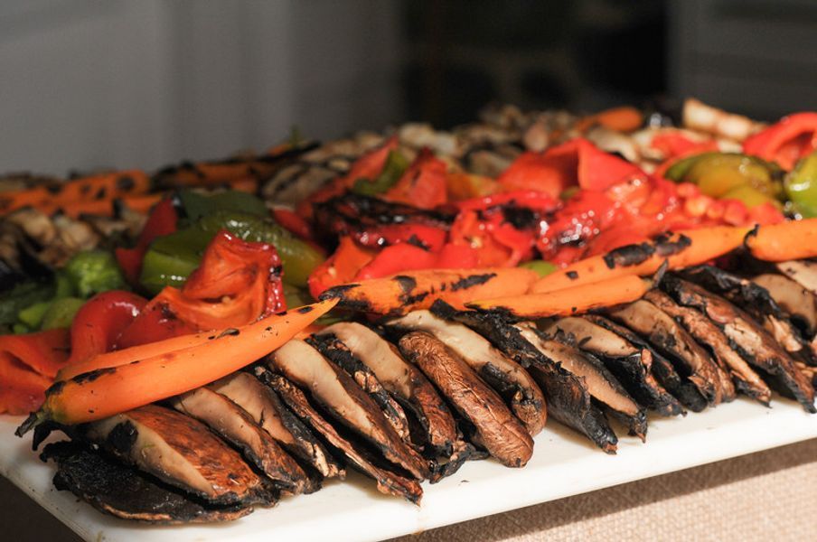 A white plate topped with sliced mushrooms carrots and peppers