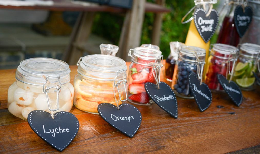 A row of jars filled with different types of fruit on a wooden table