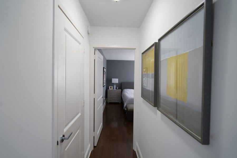 A hallway leading to a bedroom with two paintings on the wall