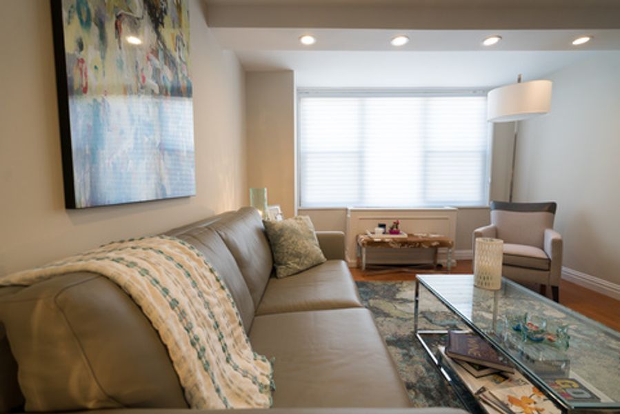 A living room with a couch, chair, coffee table and painting on the wall