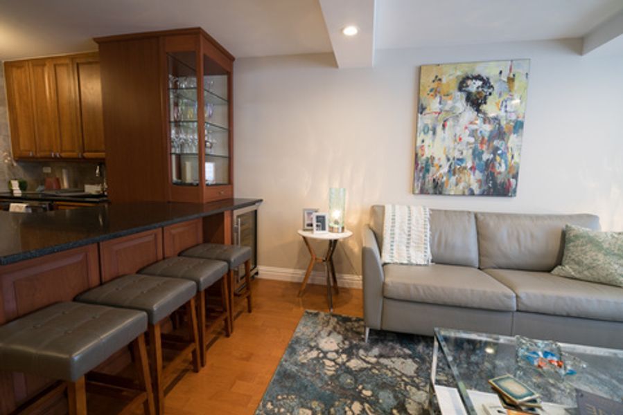 A living room with a couch, table, stools and a painting on the wall