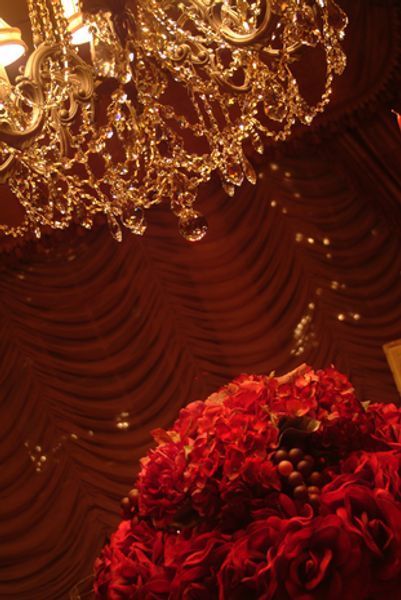 A bunch of red roses sitting under a chandelier