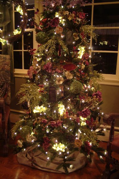 A christmas tree is decorated with flowers and lights in a living room