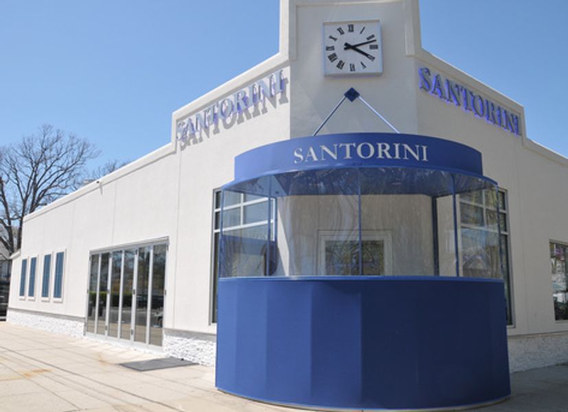 A white building with a blue awning that says santorini