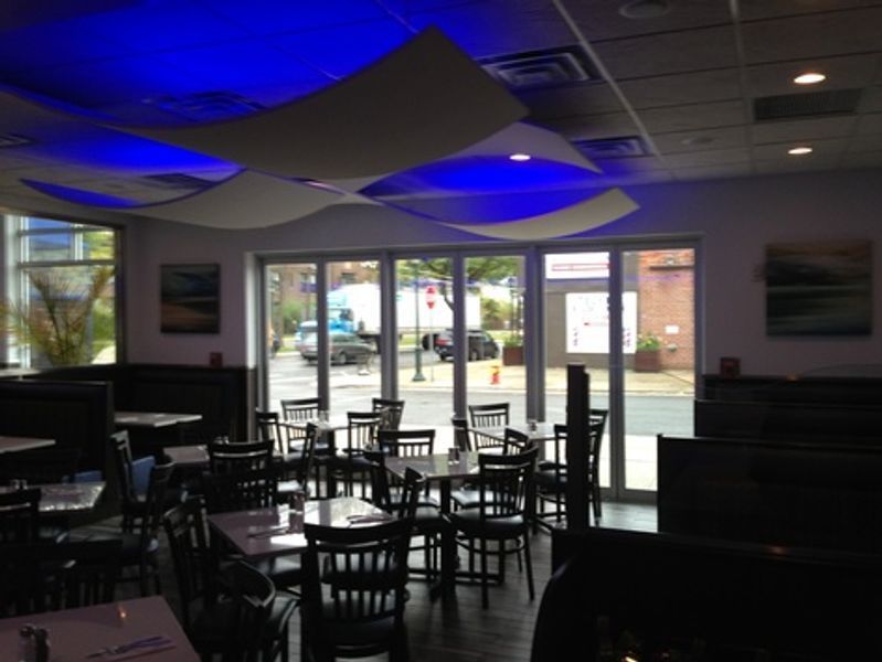 A restaurant with tables and chairs and blue lights on the ceiling