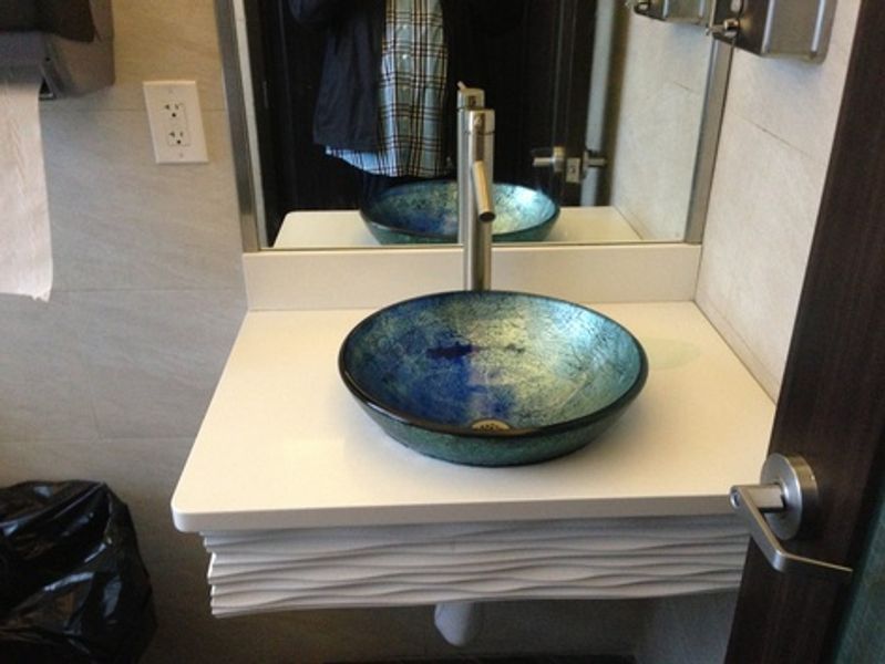 A bathroom with a round sink and a mirror