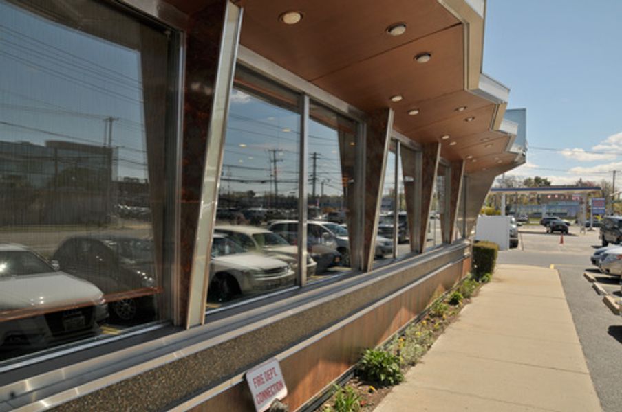 A row of cars are parked in front of a mcdonalds