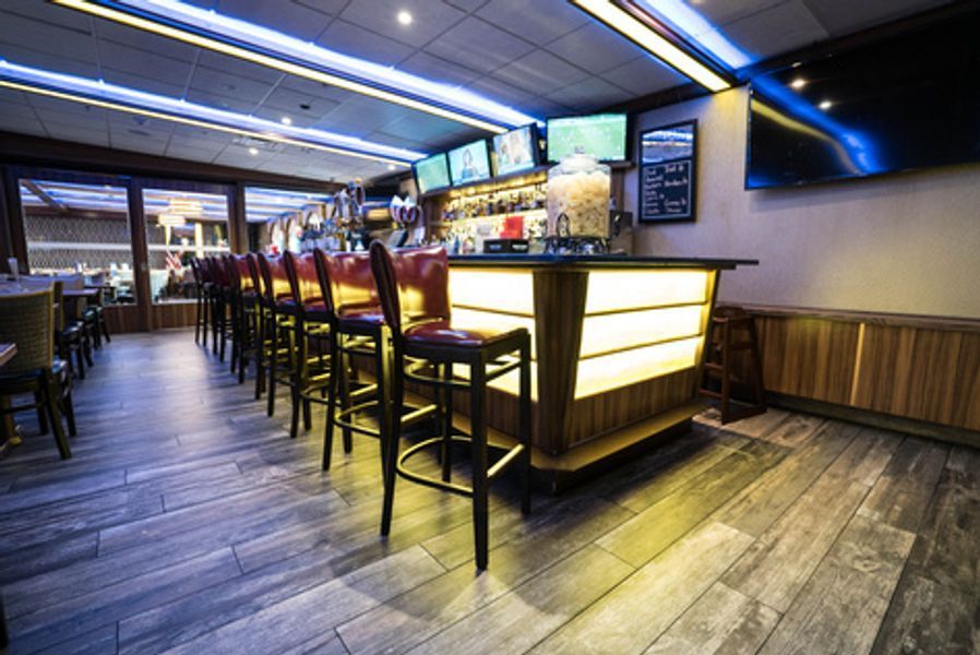 A bar with a lot of chairs and tables in a restaurant