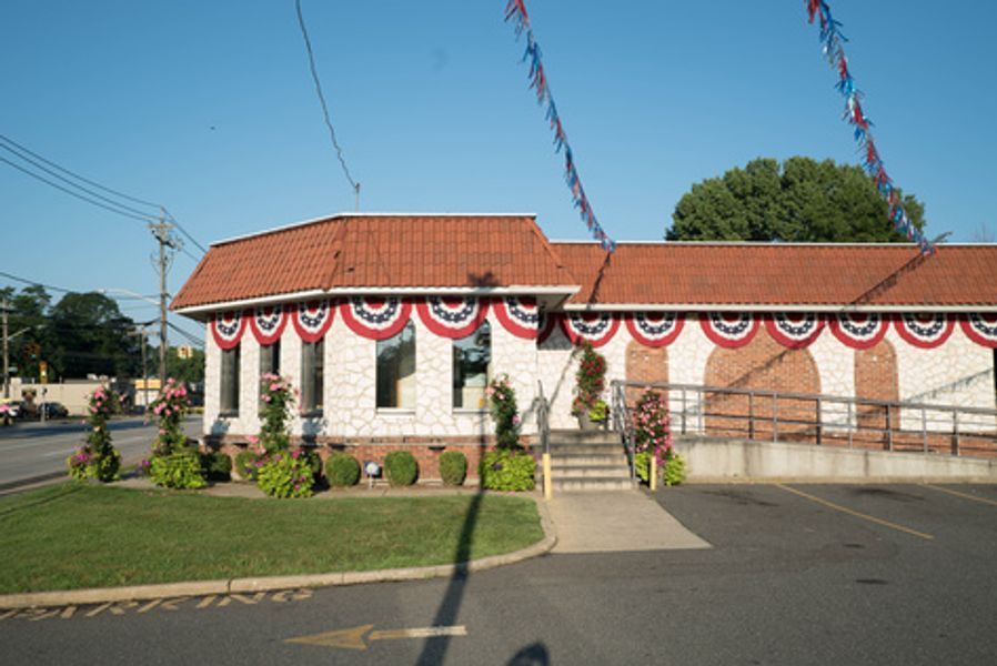A white building with a red roof is decorated with red white and blue banners