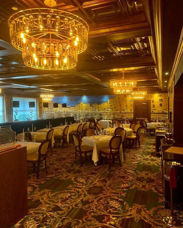 A large dining room with tables and chairs and a chandelier hanging from the ceiling.