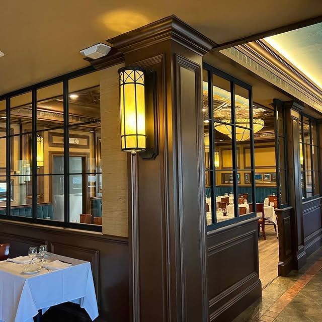 A restaurant with tables and chairs and a lamp on the wall