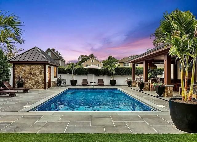 There is a large swimming pool in the backyard of a house.