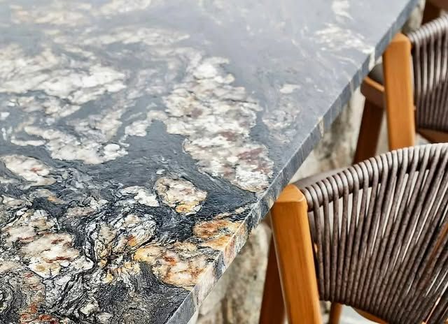 A table with a granite top and two chairs.