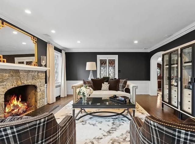 A living room with a fireplace , couch , chairs and a mirror.