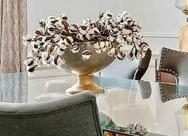 A dining room table with a vase of flowers on it.
