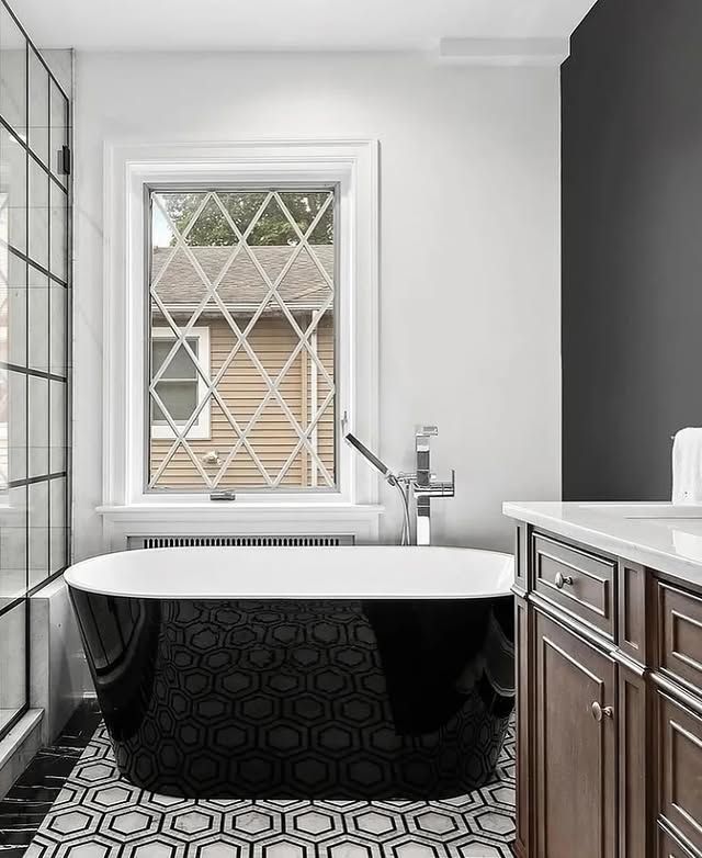A bathroom with a black tub and a window.