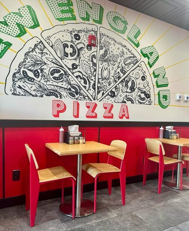 A pizza restaurant with tables and chairs and a large pizza on the wall