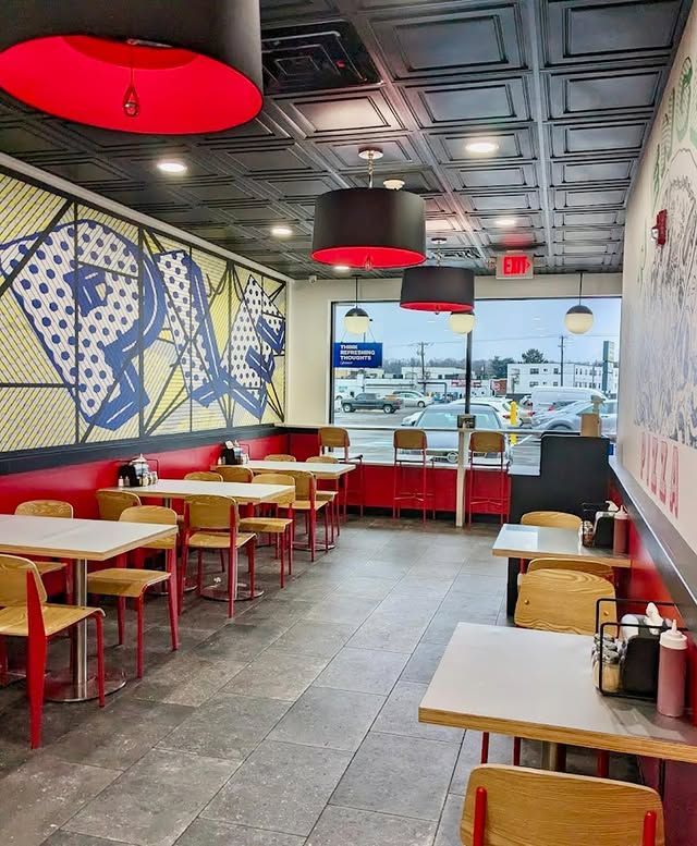 A restaurant with tables and chairs and a large window.