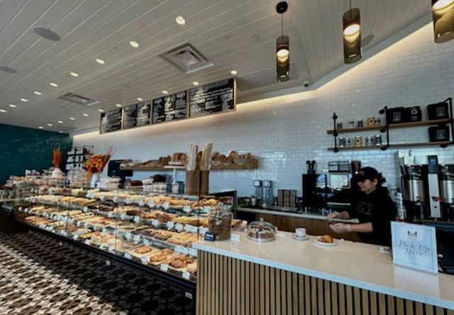 A bakery with lots of food and a woman behind the counter