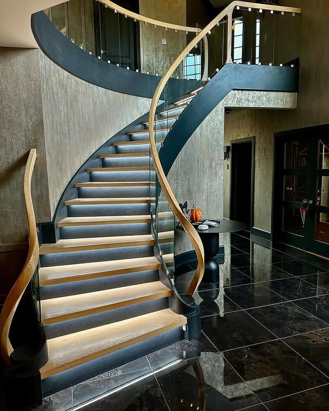 A curved staircase with a glass railing in a room.