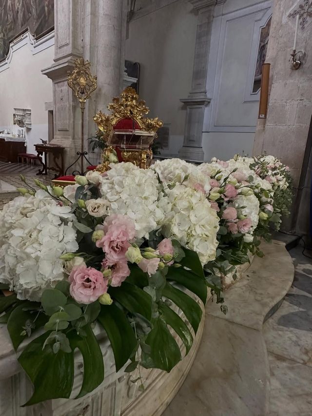 Composizioni floreali bianche e rosa che adornano la navata di una chiesa vicino all'altare.