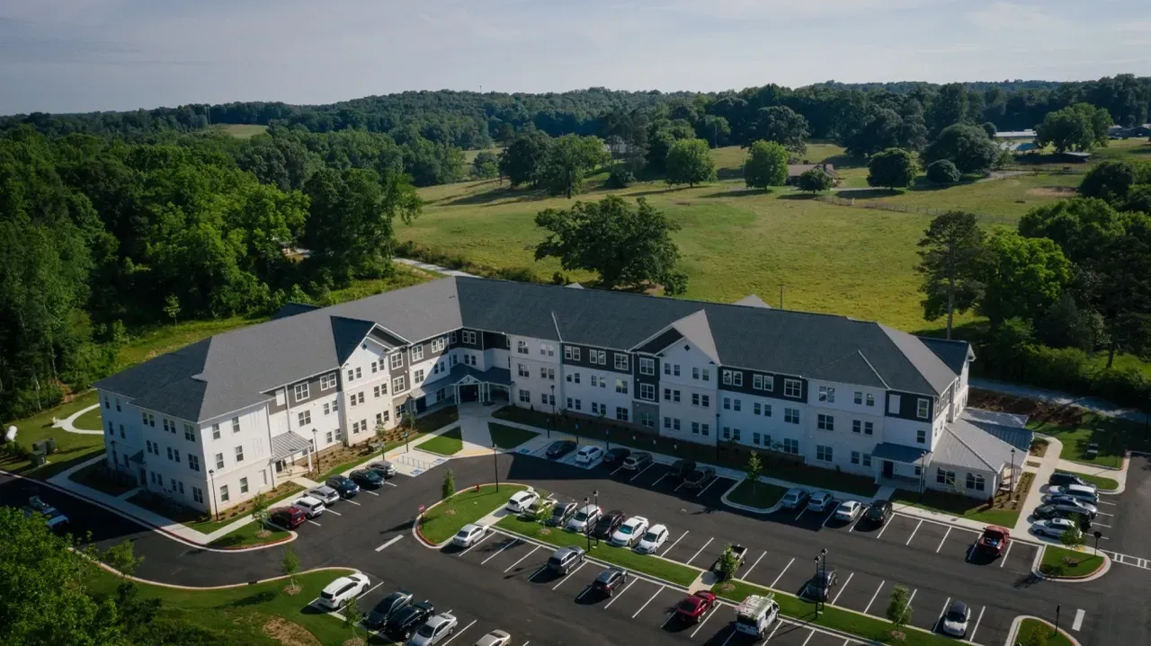 Aerial view of a large U-shaped apartment building with surrounding parking.