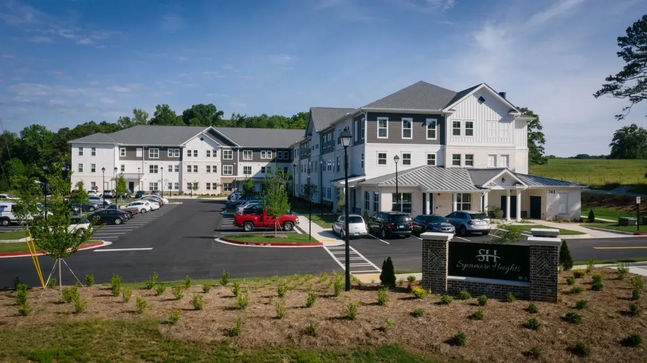 Exterior view of a modern apartment community with white buildings and a paved parking lot.