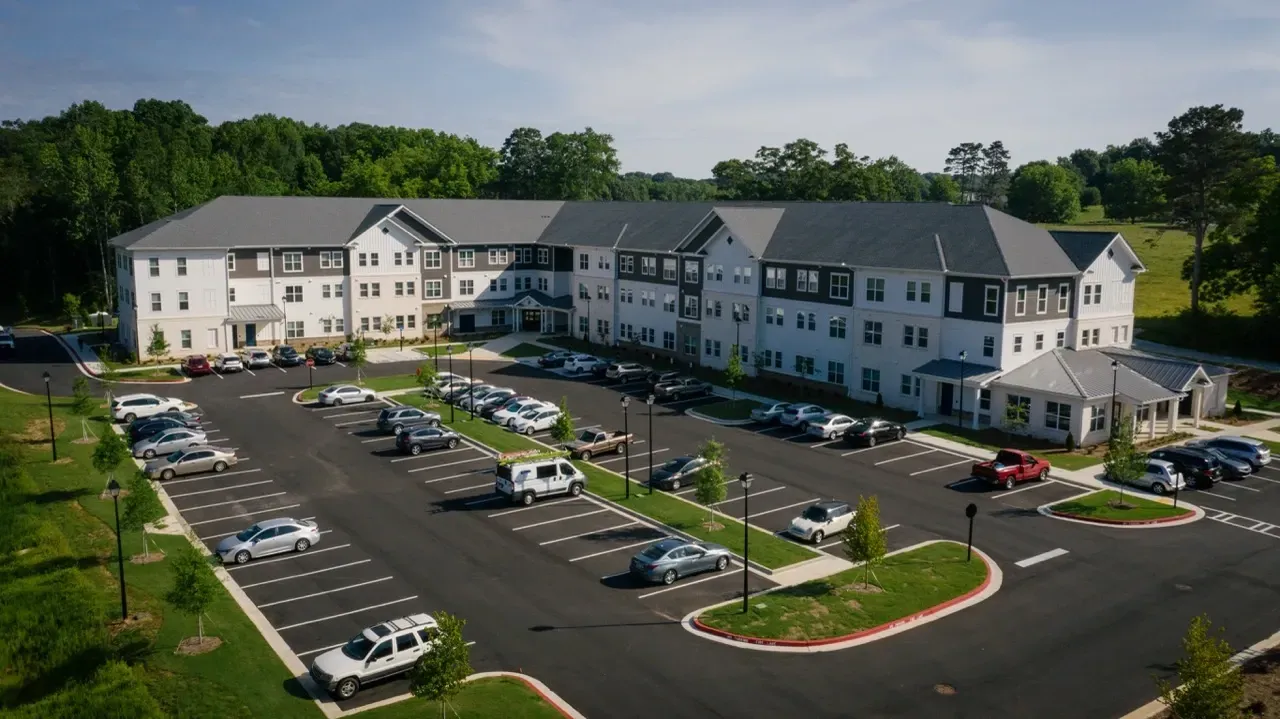 Aerial view of a modern apartment complex with a large parking lot and green spaces.