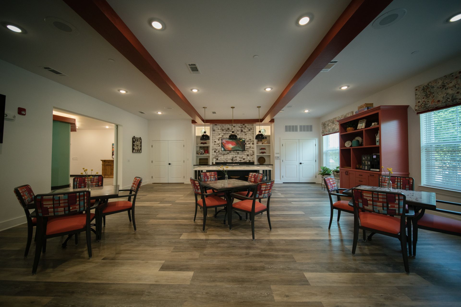 Bright modern dining room with tables, chairs, large windows, and a high coffered ceiling.
